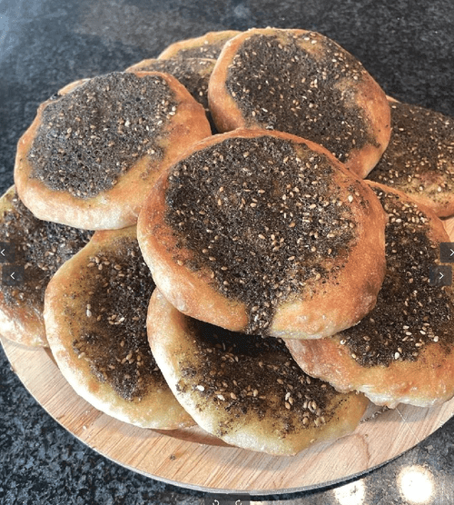 disc-shaped dark golden bread with a lot of herbs & spices on top