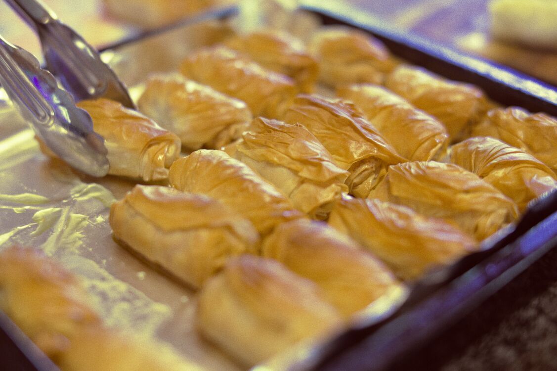 close-up of syrup-soaked baklava placed into a lined tray ready to bake